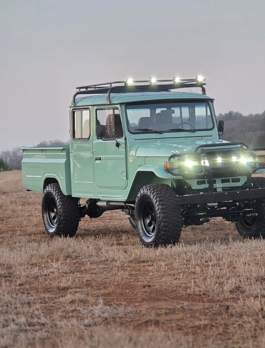 Restored Toyota Bandeirante pickup in seafoam green with roof rack and light bar