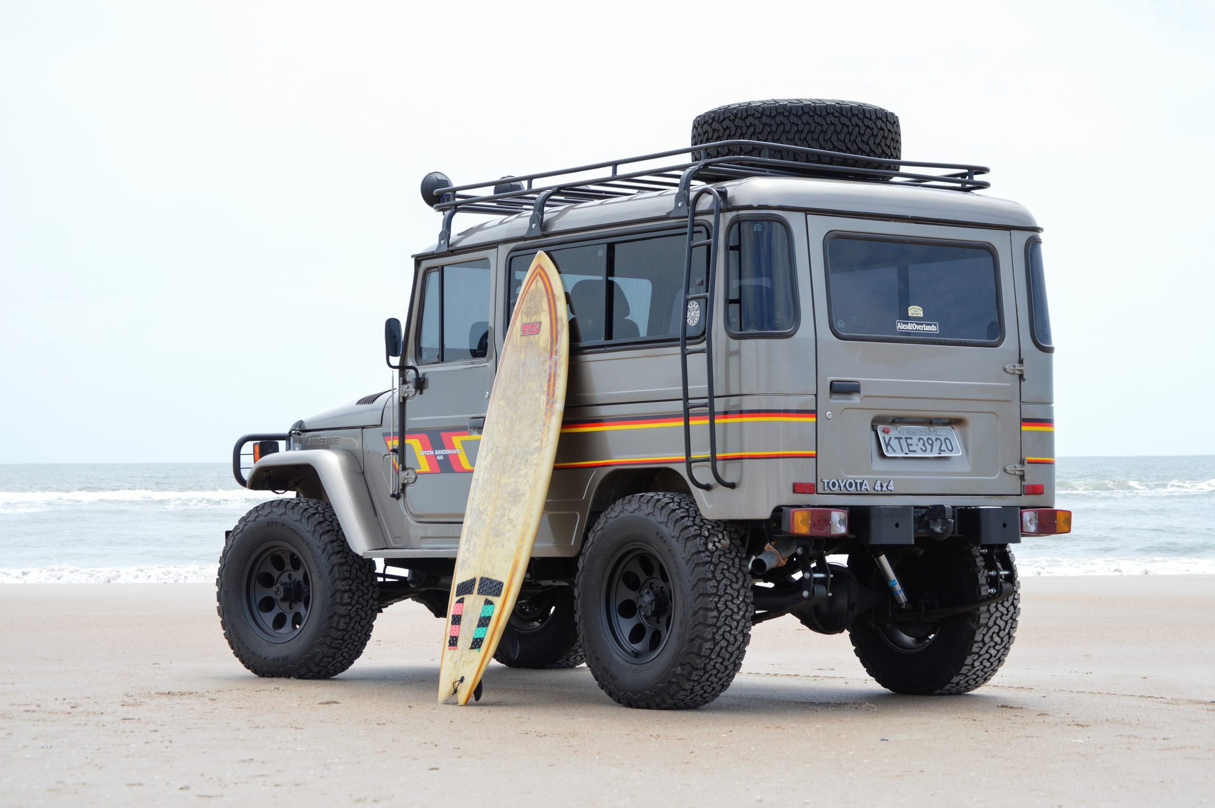 Grey Toyota Bandeirante hardtop wagon on the beach with a surfboard